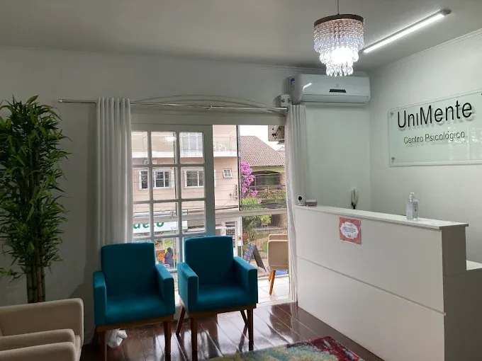 Recepção da UniMente com poltronas azul-petróleo e a placa da clínica